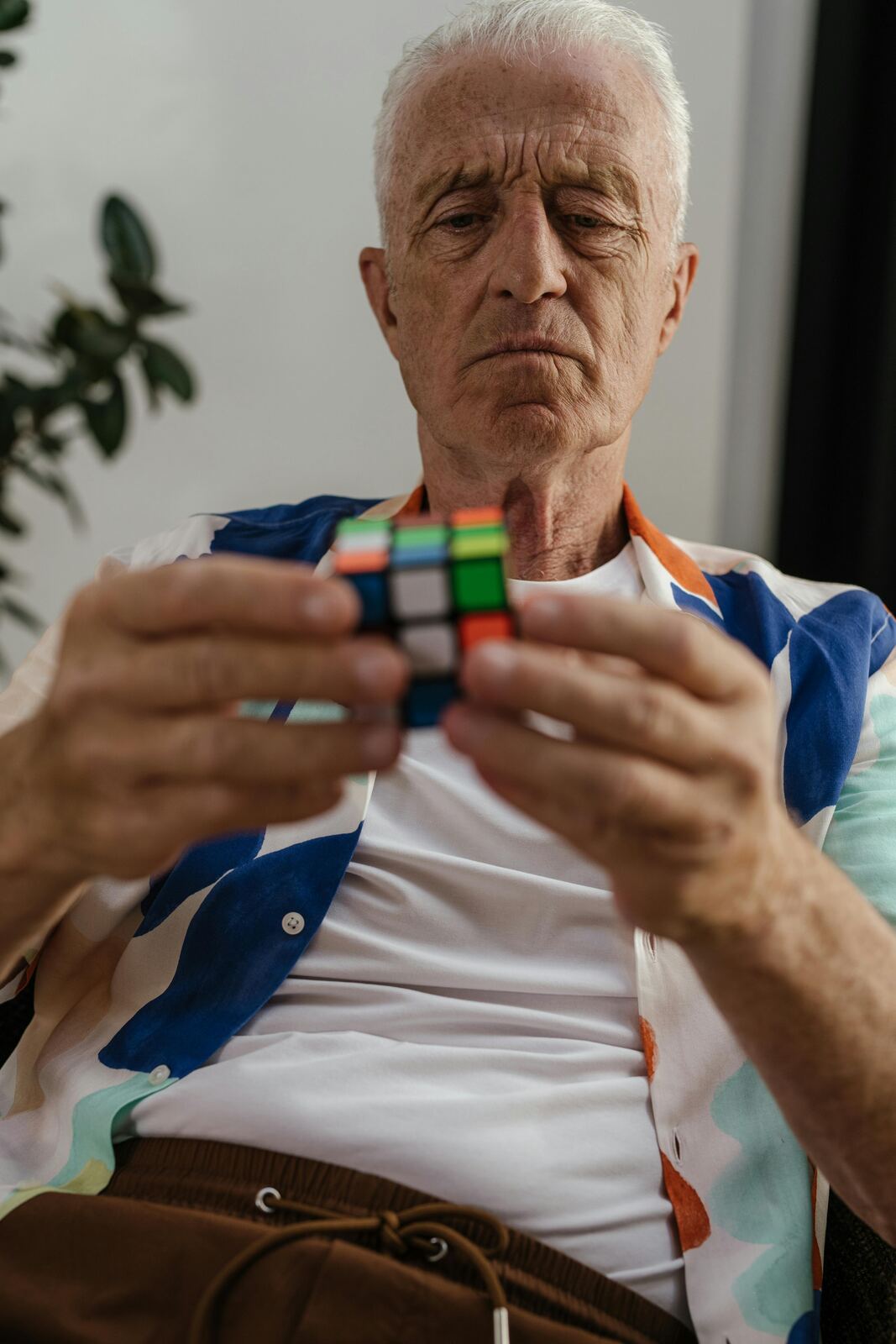 Older man focused on solving a Rubik's cube, exercising cognitive and motor coordination